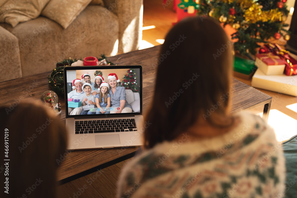 Mother and daughter making christmas laptop video call with happy multi generation caucasian family