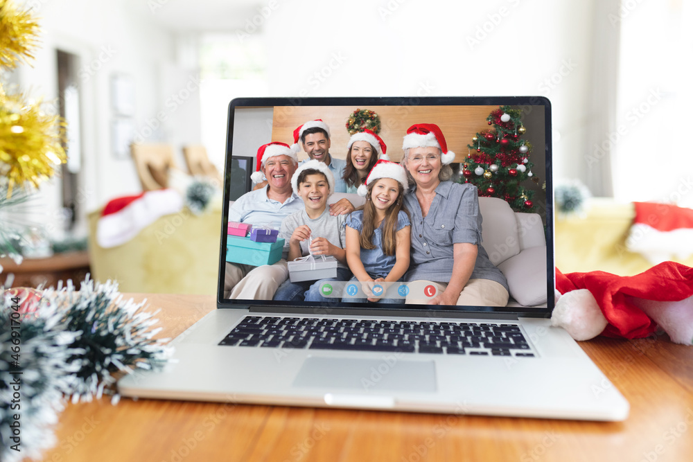 Smiling multi generation caucasian family in santa hats on laptop christmas video call screen