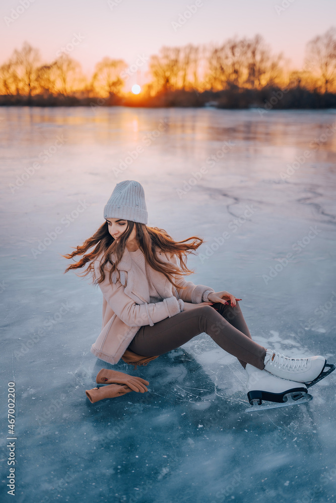 a girl in skates is sitting on the ice. winter holidays