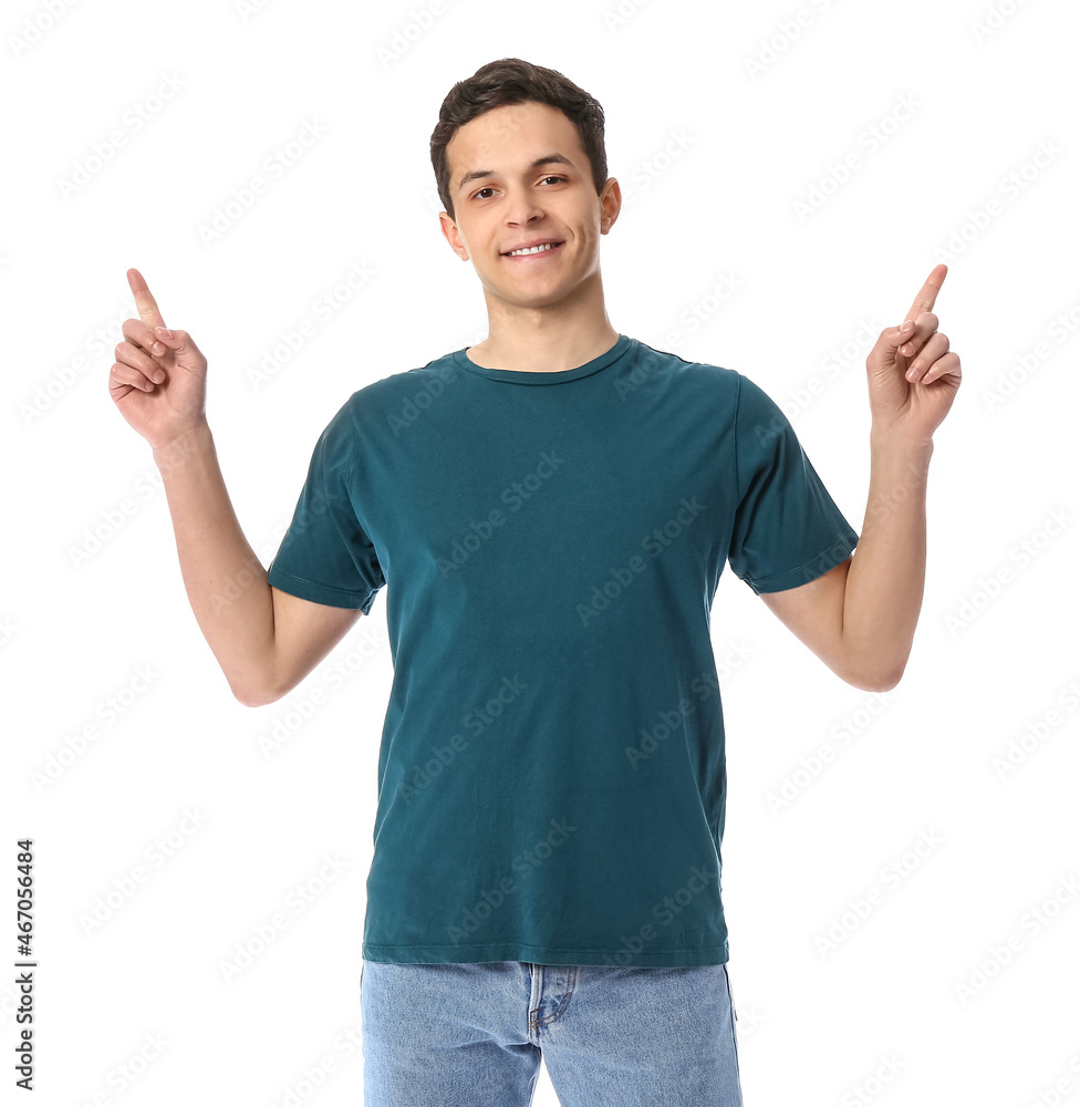 Handsome young man in stylish t-shirt pointing at something on white background