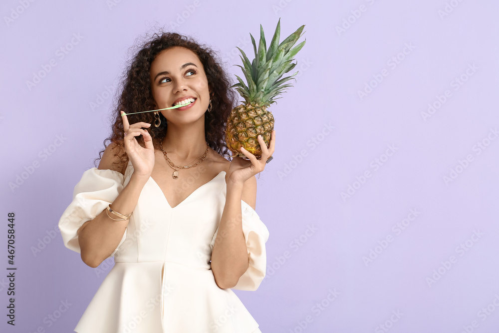 African-American woman with chewing gum and pineapple on color background