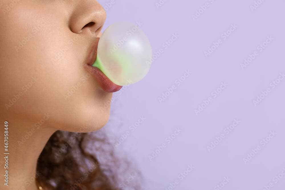 African-American woman with chewing gum on color background, closeup