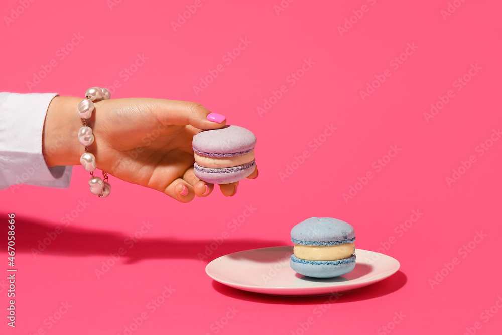 Woman with beautiful manicure and stylish jewelry holding macaron on color background