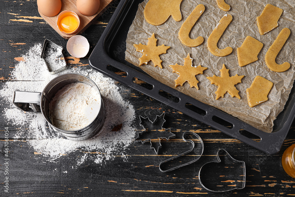 Baking sheet with raw Christmas cookies on dark wooden background