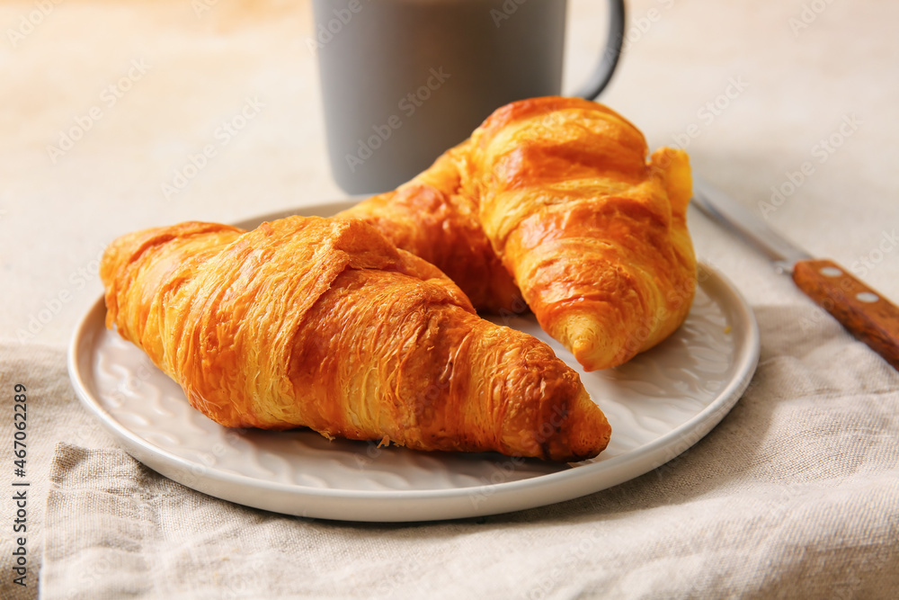 Plate with delicious croissants on white background