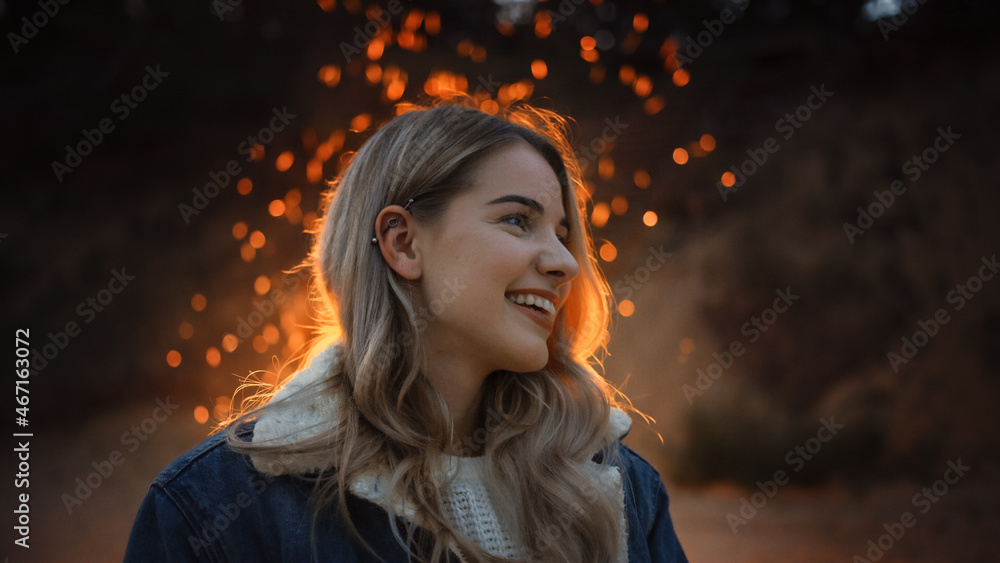 Portrait of a Young Beautiful Blond Woman in a Romantic Evening Atmosphere with a Campfire in the Ba