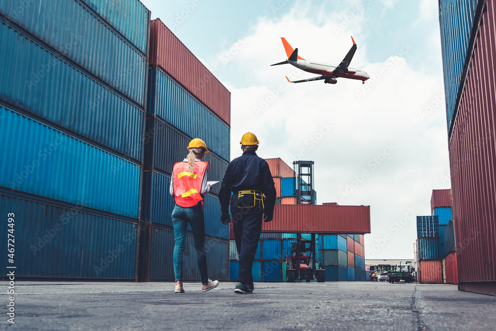 Industrial worker works with co-worker at overseas shipping container port . Logistics supply chain 