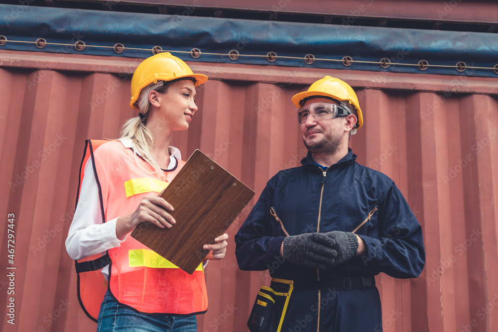 Industrial worker works with co-worker at overseas shipping container yard . Logistics supply chain 