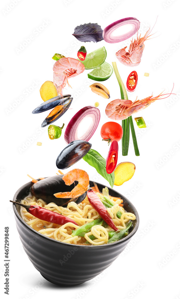 Bowl of tasty Thai soup with flying ingredients on white background