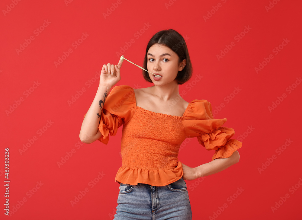 Young woman with chewing gum on color background