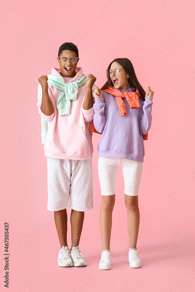 Emotional stylish young couple in hoodies on pink background