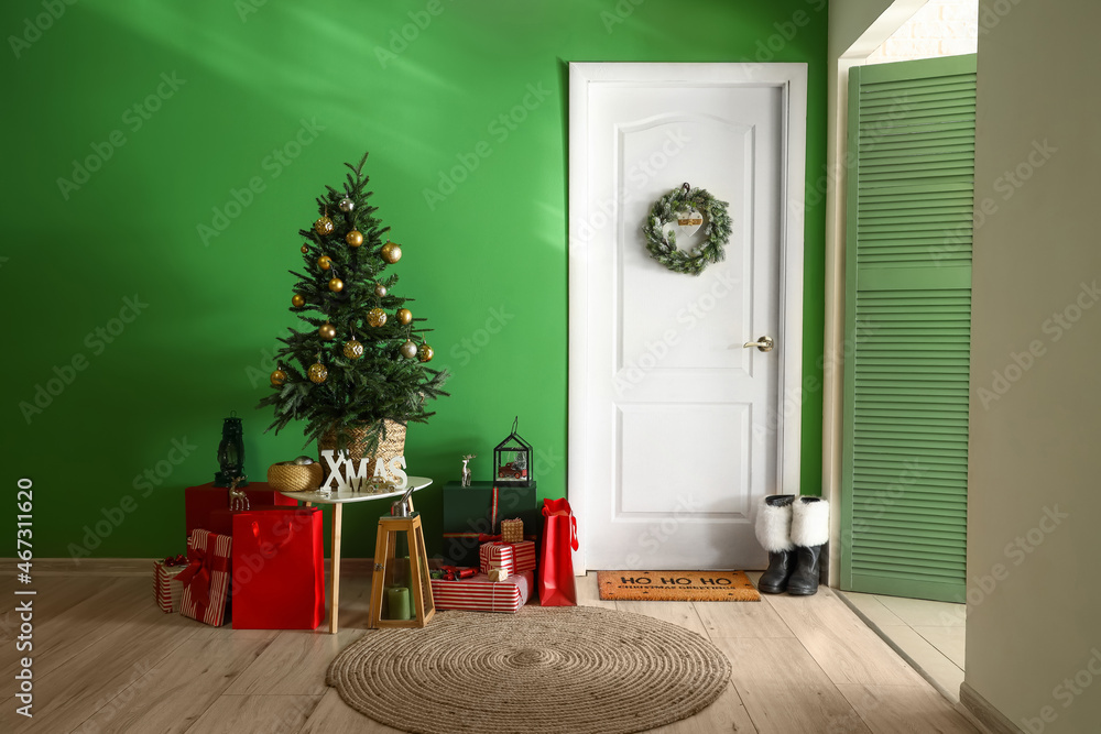 White door with wreath, Christmas tree and gifts near green wall