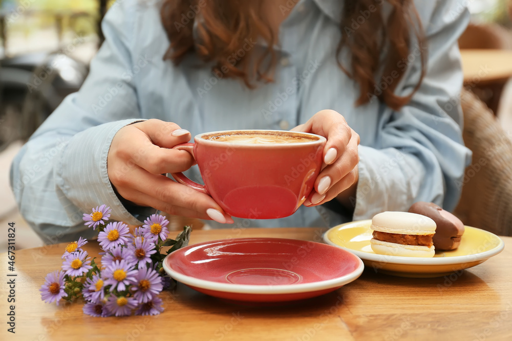 Woman drinking delicious coffee at table in cafe