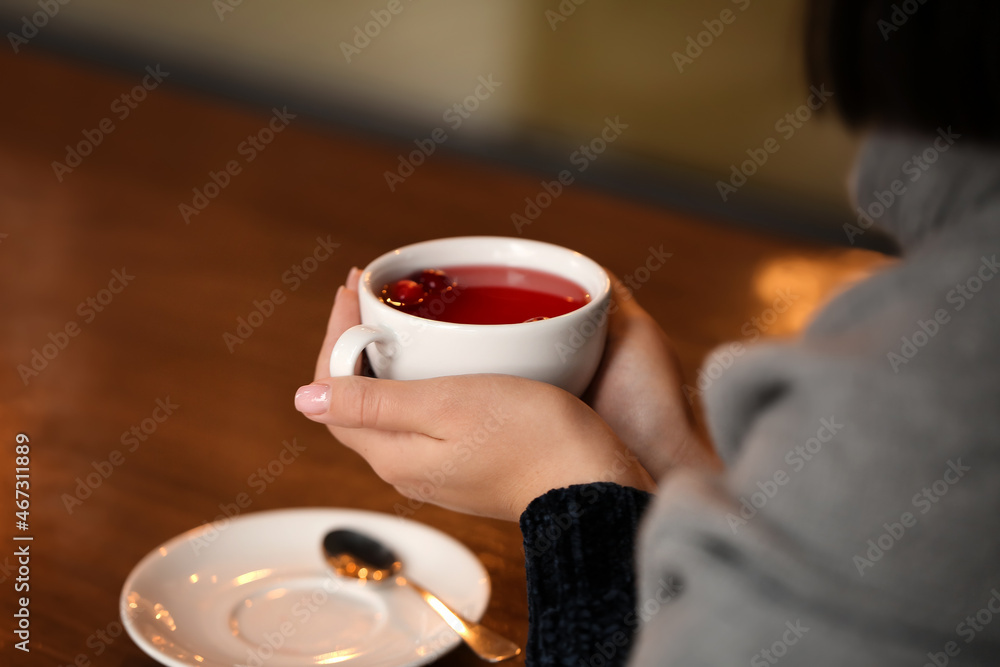 年轻女子在咖啡馆的餐桌上喝茶