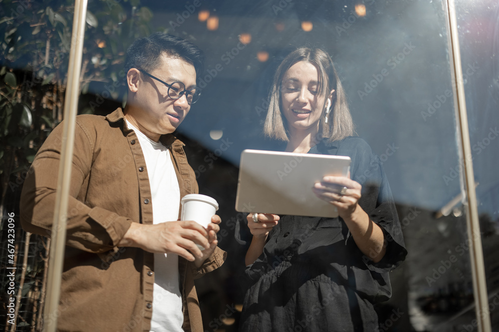 Multiracial business people watching something on digital tablet inside unknown building. Concept of