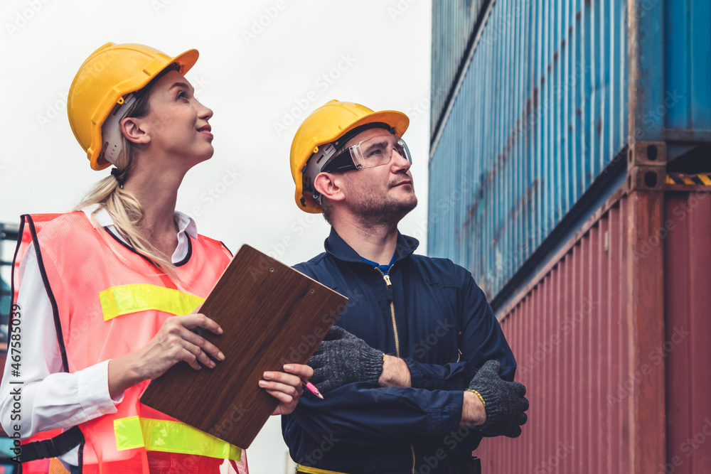 Industrial worker works with co-worker at overseas shipping container yard . Logistics supply chain 