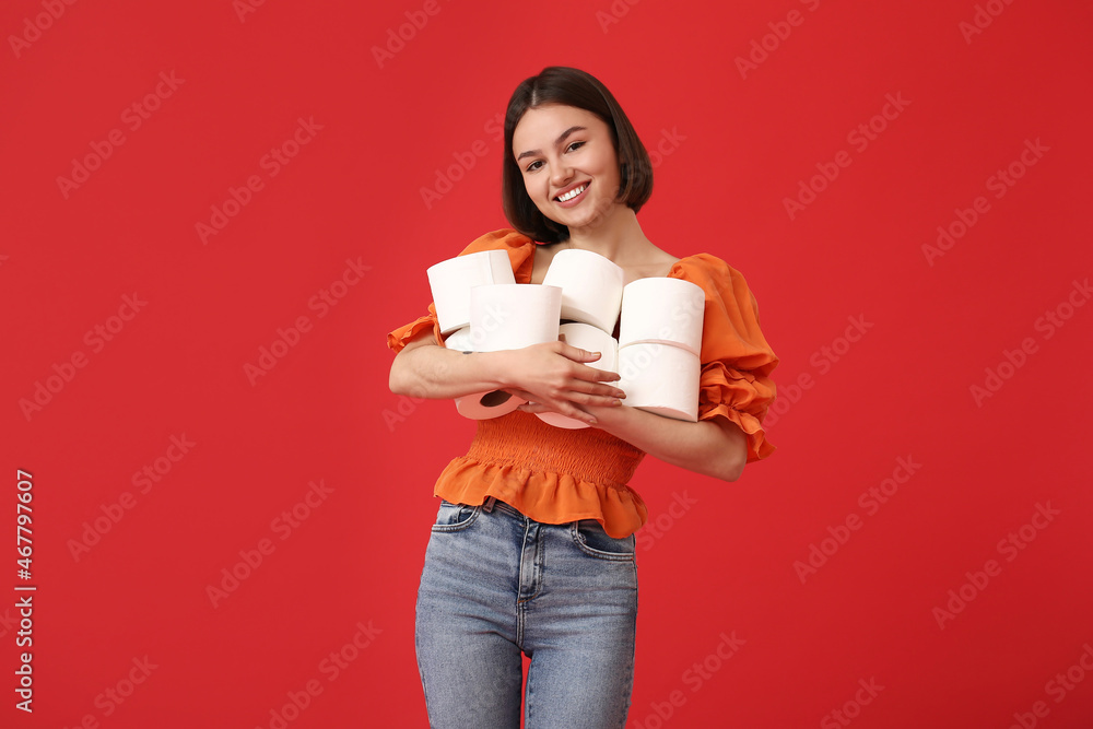 Young woman with many rolls of toilet paper on color background