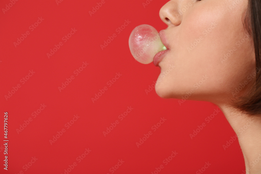 Young woman with chewing gum on color background, closeup