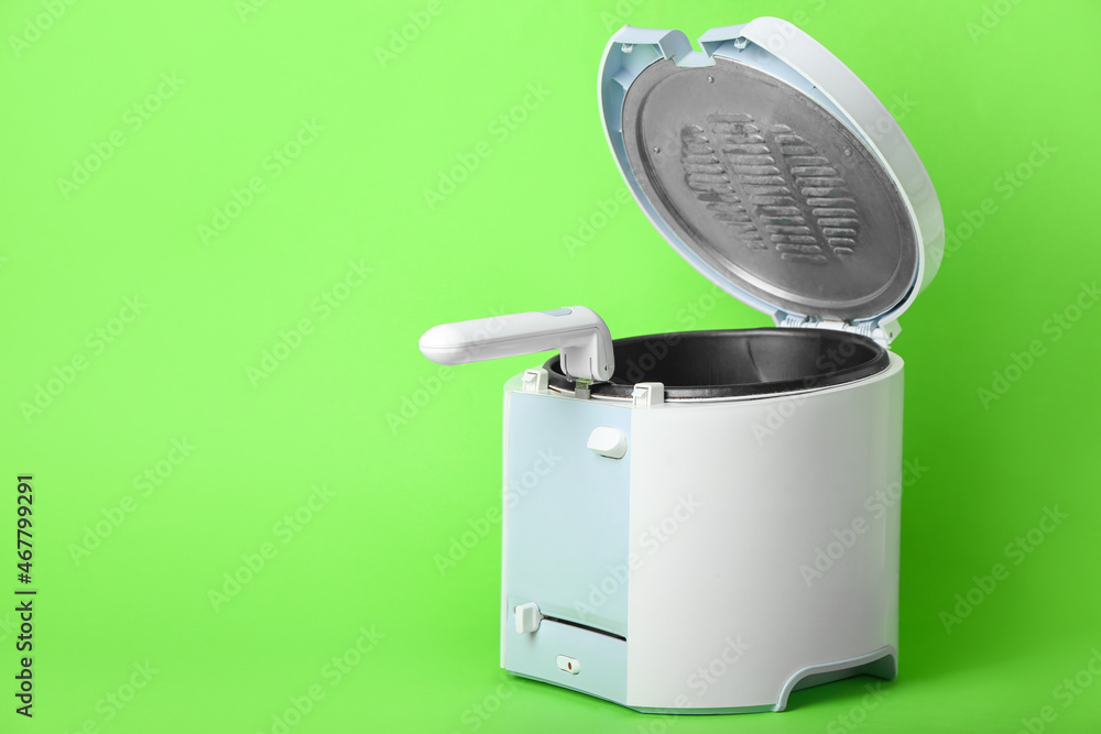 Modern deep fryer on color background