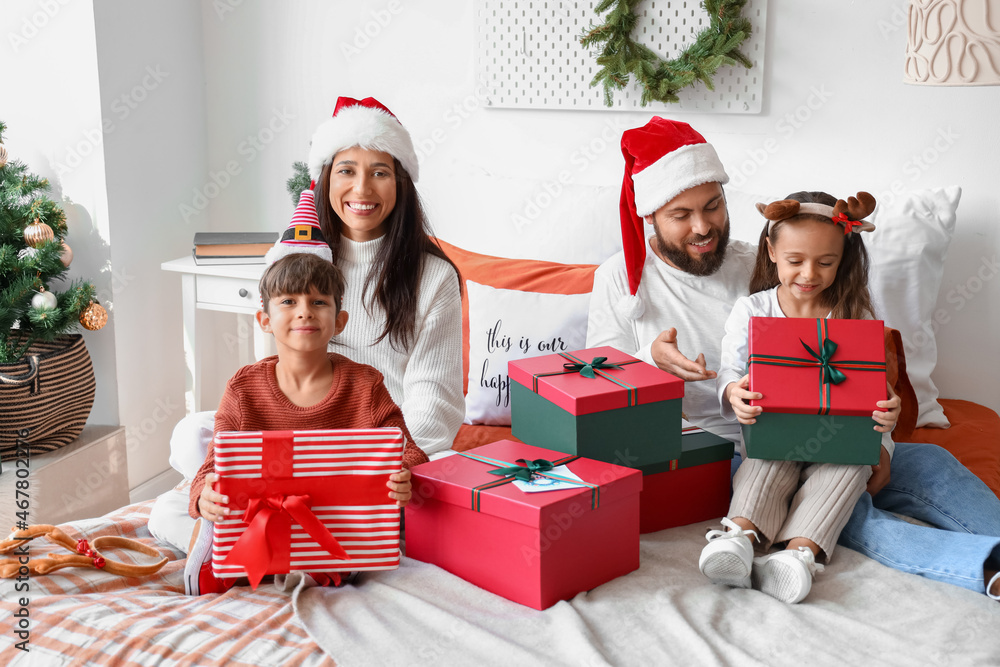 Happy family with Christmas gifts in bedroom