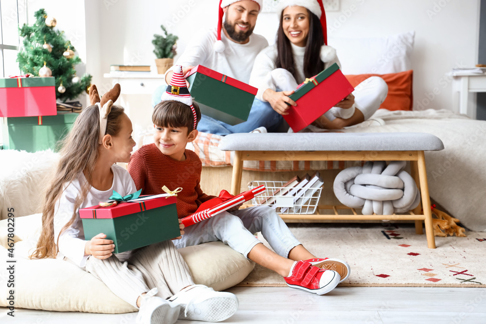 Happy family with Christmas gifts in bedroom