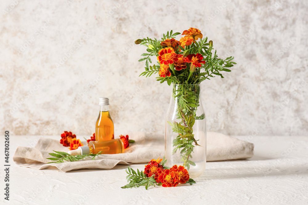 Bottle with bouquet of marigold flowers on table