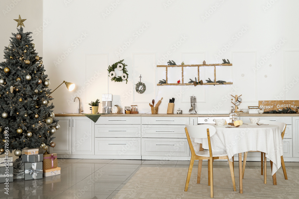 Christmas tree with gifts in interior of light kitchen