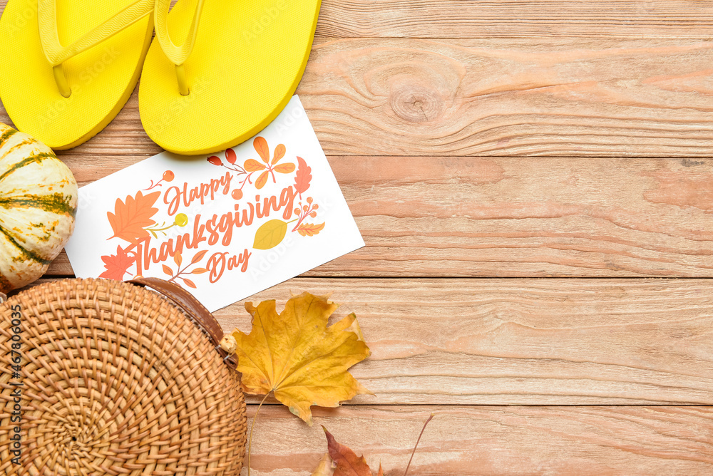 Stylish bag, pumpkin, flip flops, dry leaves and paper card with text HAPPY THANKSGIVING DAY on wood