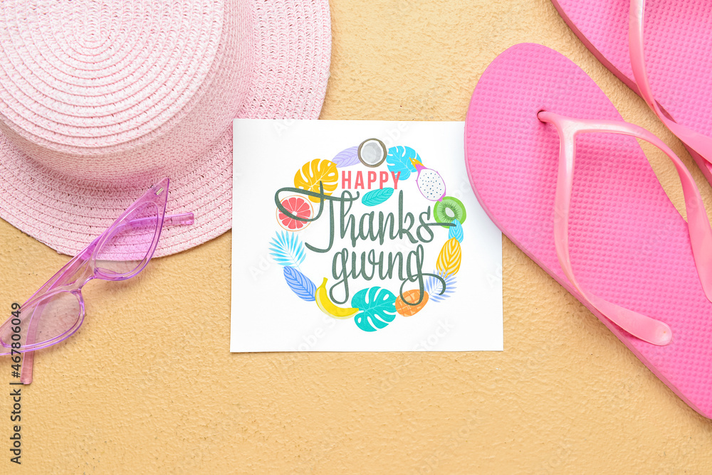 Beach hat, sunglasses, flip flops and paper card with text HAPPY THANKSGIVING on color background