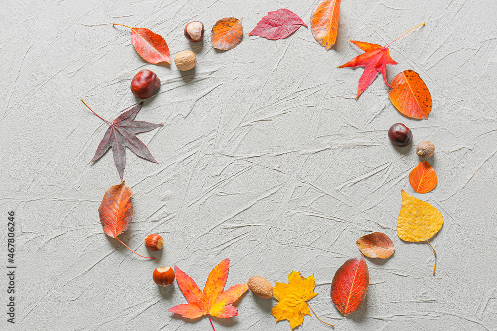 Frame made of autumn leaves and nuts on grey background