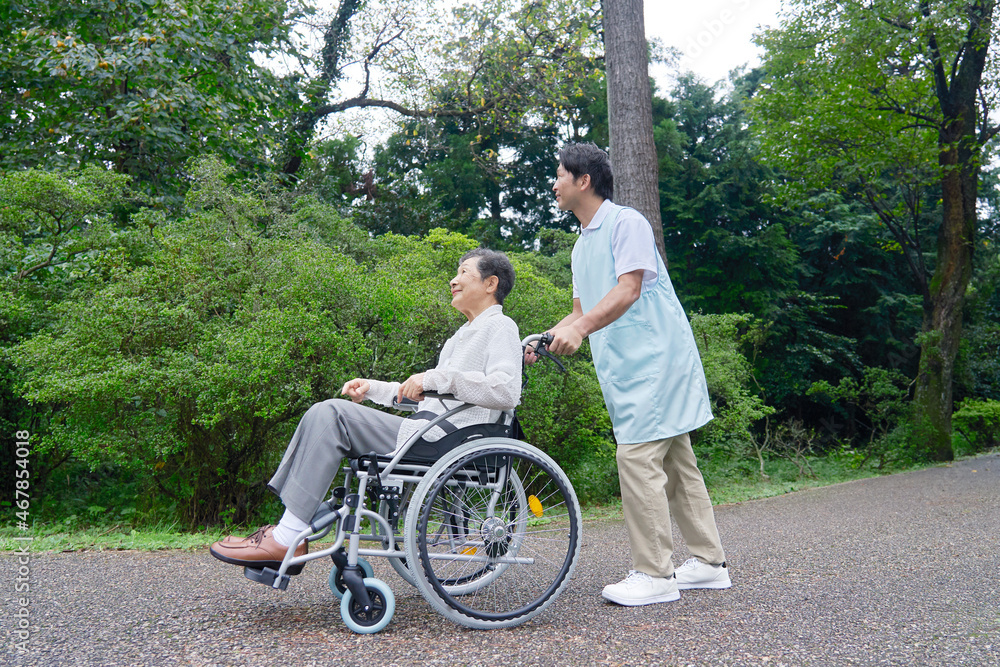 介護士と車椅子に乗る高齢者　屋外