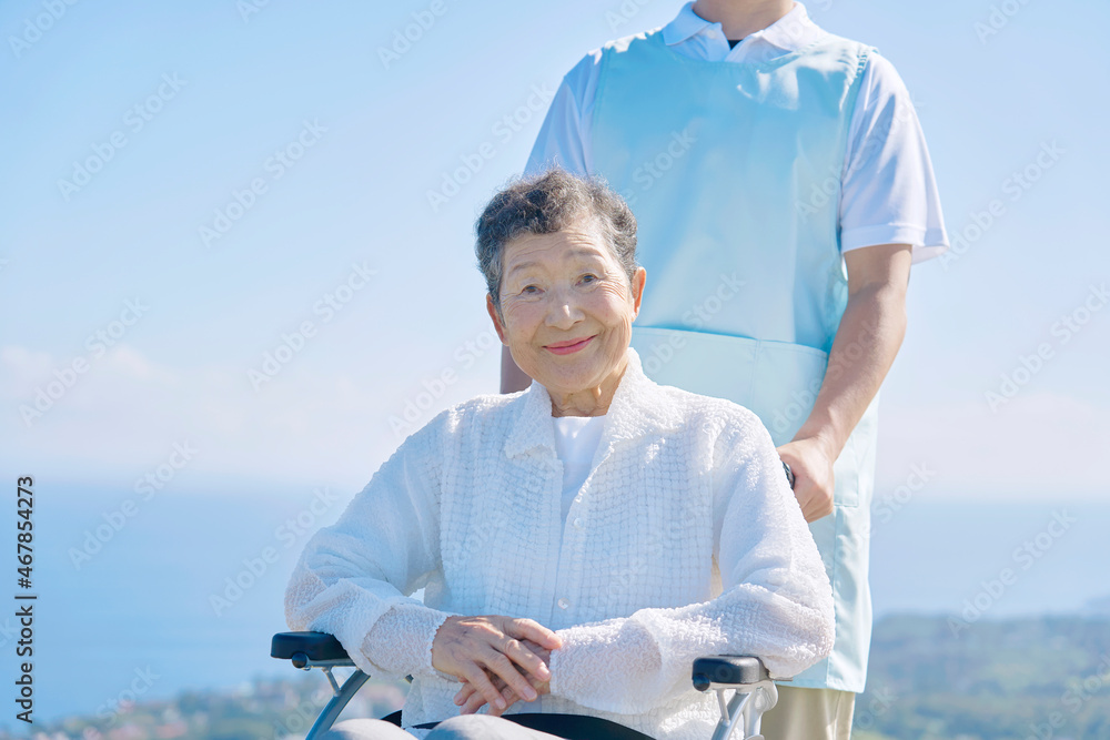 介護士と車椅子に乗る高齢者　屋外