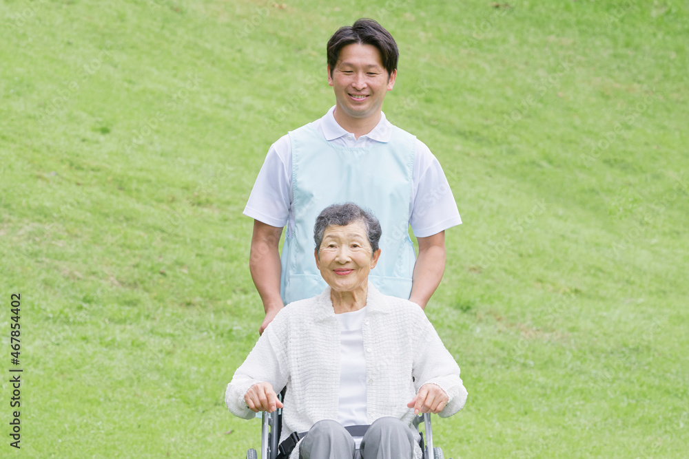 介護士と車椅子に乗る高齢者　屋外