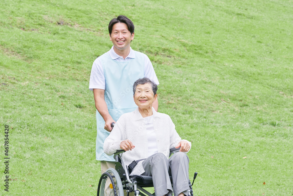 介護士と車椅子に乗る高齢者　屋外