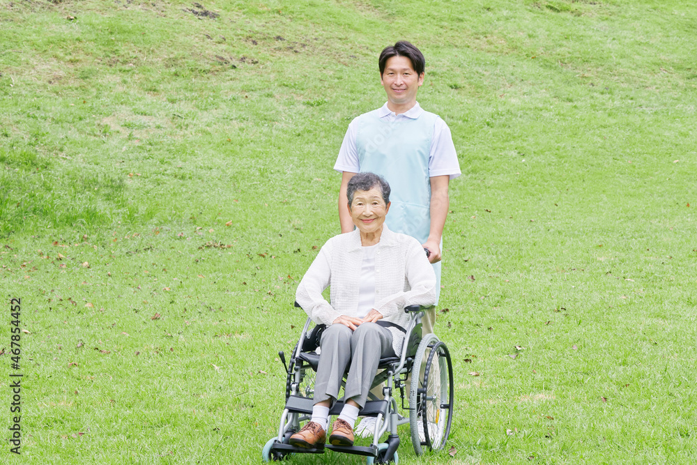 介護士と車椅子に乗る高齢者　屋外