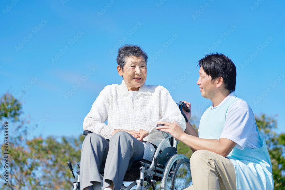 介護士と車椅子に乗る高齢者　屋外