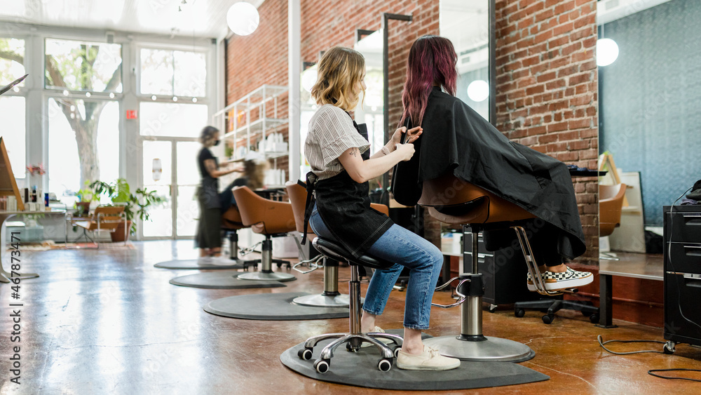 Hairstylist trimming a hair of a customer