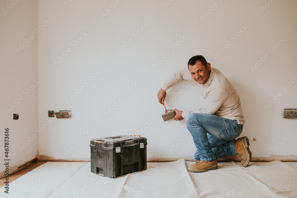 Electrician fixing the power outlet on the wall