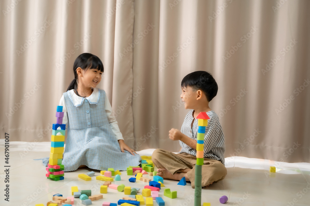 Little siblings playing colorful wooden blocks in home,Sitting on floor, Sister and younger brother 