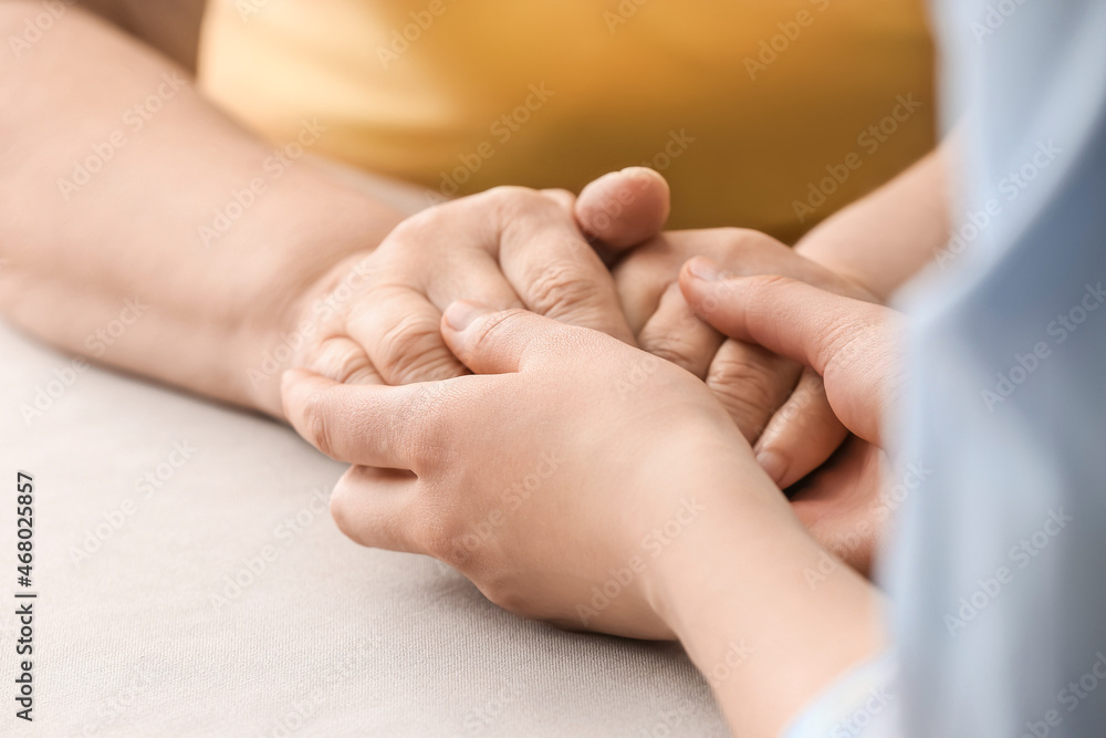 Young woman holding hands of grandmother at table