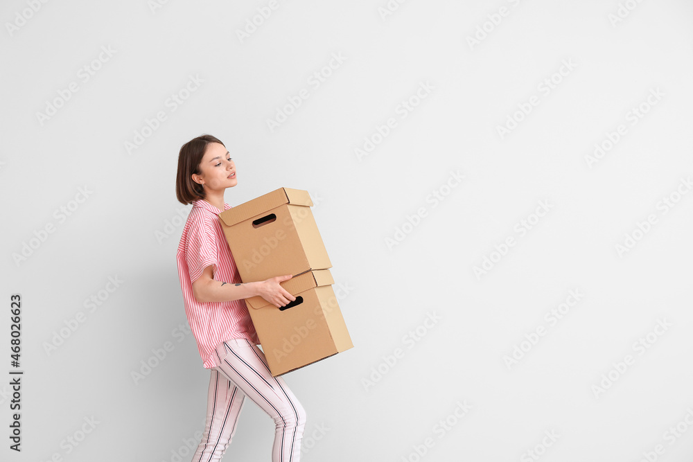 Young woman with wardrobe boxes on light background