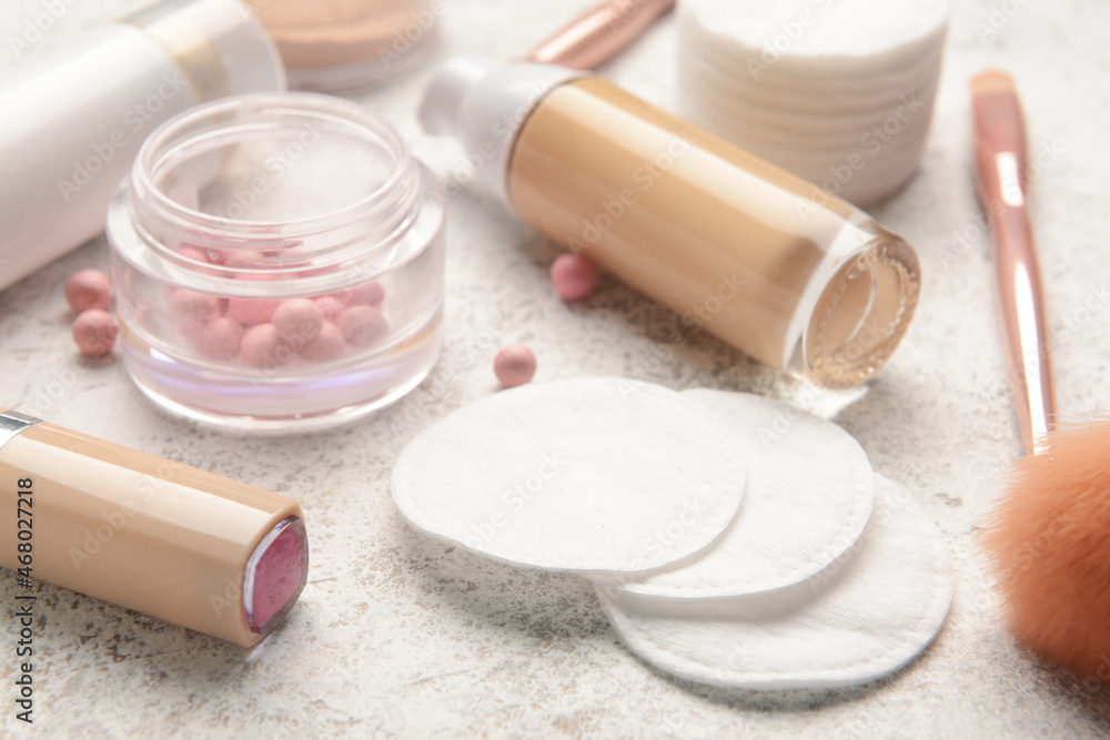 Different decorative cosmetics and cotton pads on light background, closeup