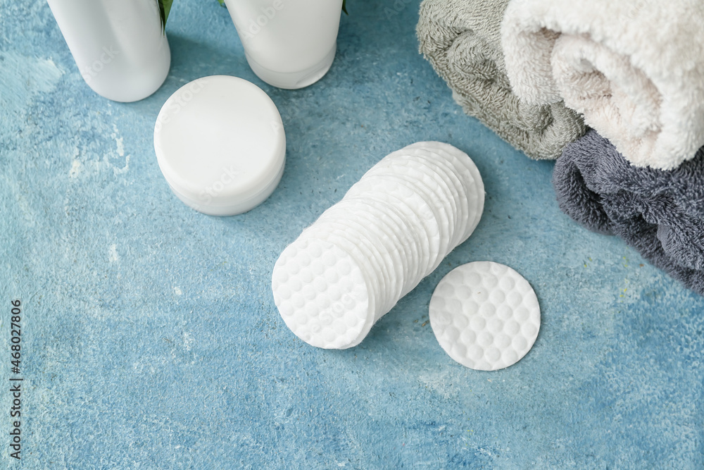 Cotton pads and towels on color background