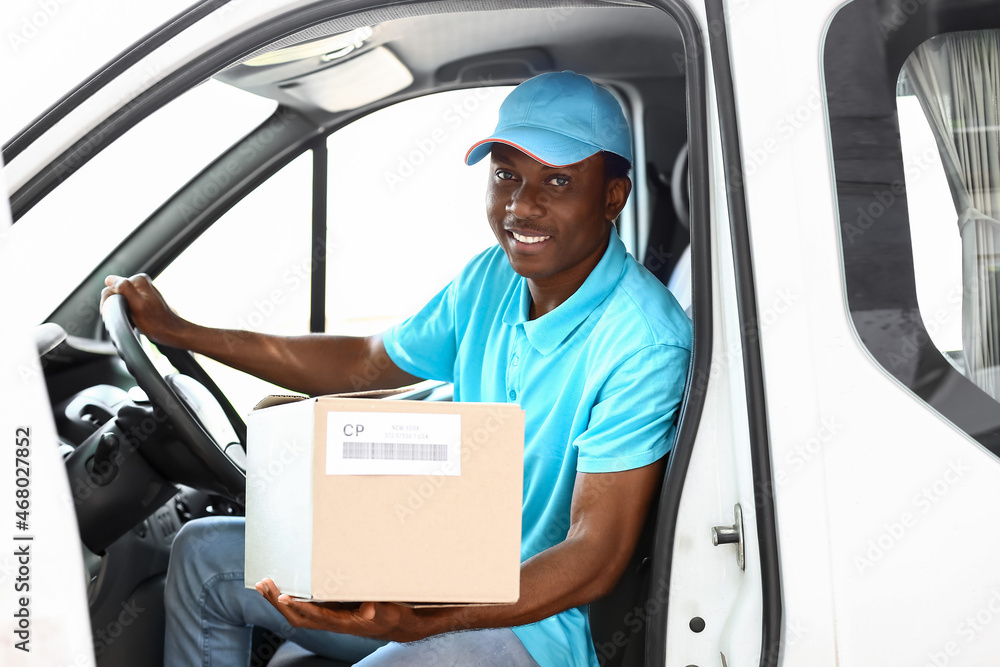 African-American courier of delivery company sitting in car