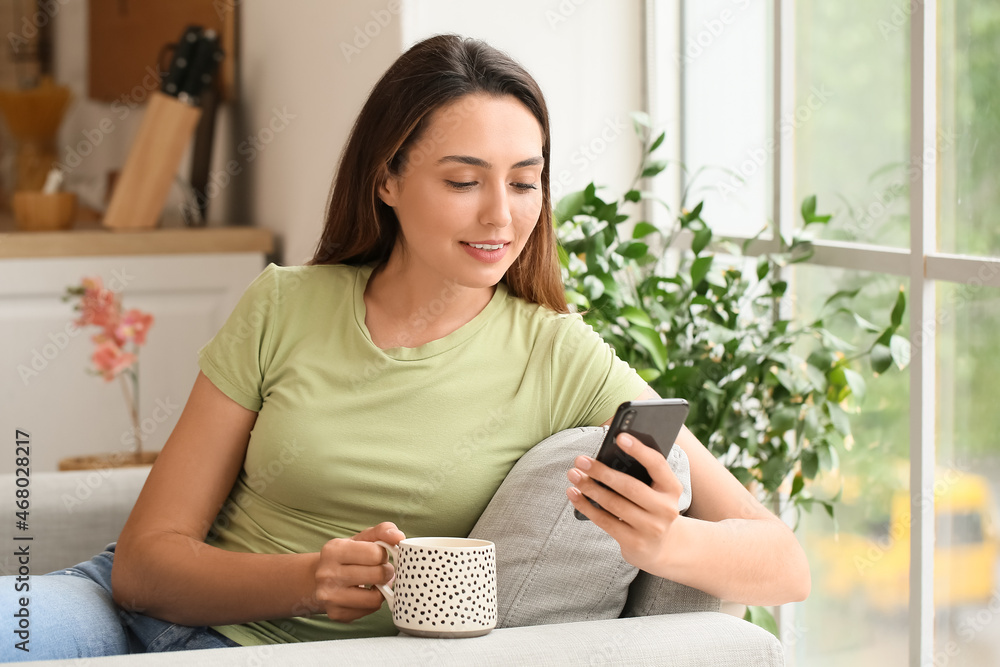 Morning of beautiful woman with phone drinking coffee at home