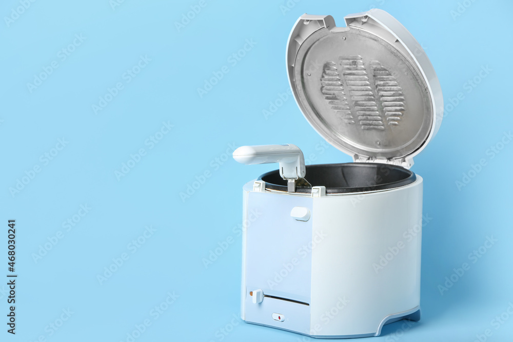 Modern deep fryer on color background