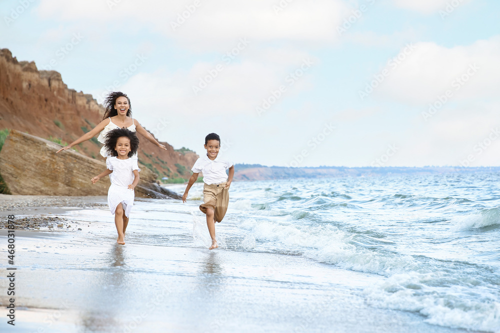 African-American children with mother running on sea beach