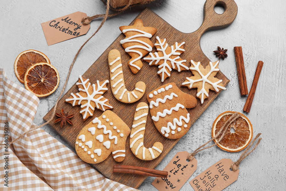 Board with Christmas gingerbread cookies on light background