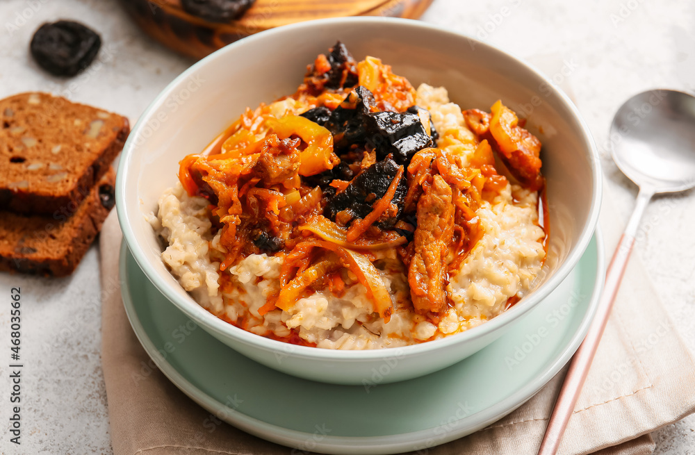 Bowl with delicious oatmeal, gravy with beef and prunes on table, closeup