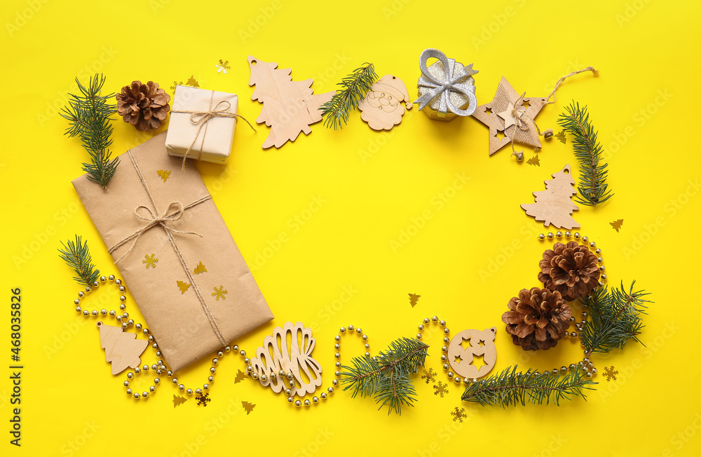 Frame made of Christmas decor, gift and fir branches on yellow background